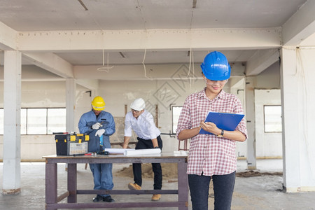 建筑工程师团队作安全信托小组负责在建筑工地硬帽子保护主任和土建工程师概念上安装白色黄全硬帽保设备C建筑工程师团队建设者人们体图片