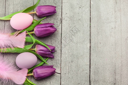 多于木板四月粉色东方鸡蛋和木制桌边紫色郁金香的顶端视图图片