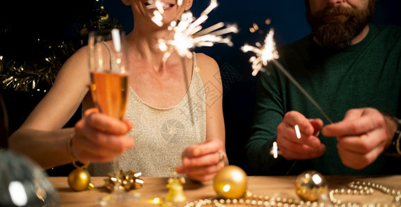 幸福的情侣拿着火花和香槟杯新年派对玻璃保持黑色的图片