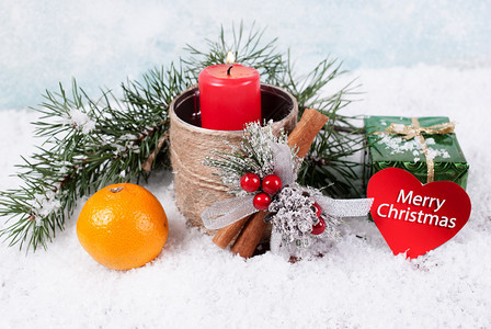 问候装饰柑橘红蜡烛礼品盒橘子和雪地背景的圆木枝印有贺卡图片