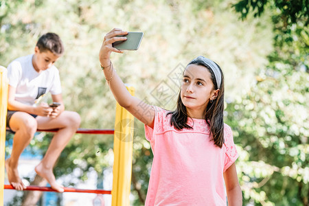 服用女孩带着手机在公园里拍自技术愉快图片