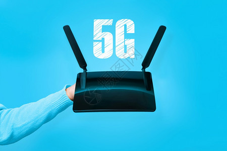 连接器手持黑色wifi路由器和蓝色背景上5G的刻字电缆互联网图片