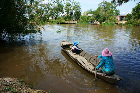 每天越南湄公河三角洲乡村风景中越南妇女搭乘小孩上街用木船学女儿和母亲坐着与竹一起渡河在湄公三角洲的越南农村地貌经过叉图片
