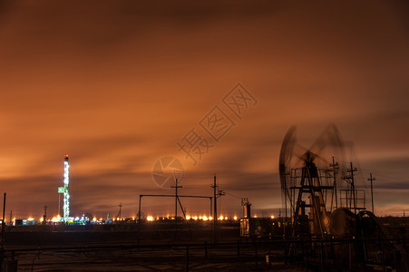 行业夜间天空背景的油泵插孔和钻井机械工作图片