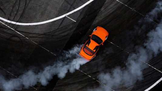在沥青赛道上漂流燃烧轮胎产生的大量烟雾空中最高视角汽车竞赛路燃尽图片