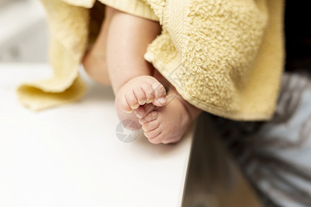 黄色的脚趾美丽用黄毛巾闭紧婴儿腿图片