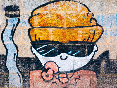 文化城市的写作男孩用太阳眼镜涂鸦奶油和橙色帽子靠近一根大弯曲的香烟图片