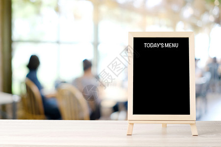 今日股菜单黑板招牌在模糊咖啡店餐馆的桌上有人们背景白黑纸板模拟背景食物和饮料背景概念布兰克粉笔板模拟背景食物和饮料背景概念内部的图片