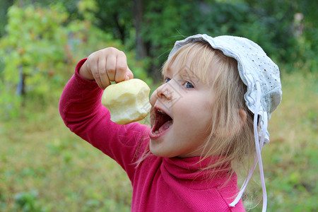 年轻的吃苹果小宝手里拿着它手里拿着被啃过的苹果宝试图咬成熟的苹果食物肖像图片