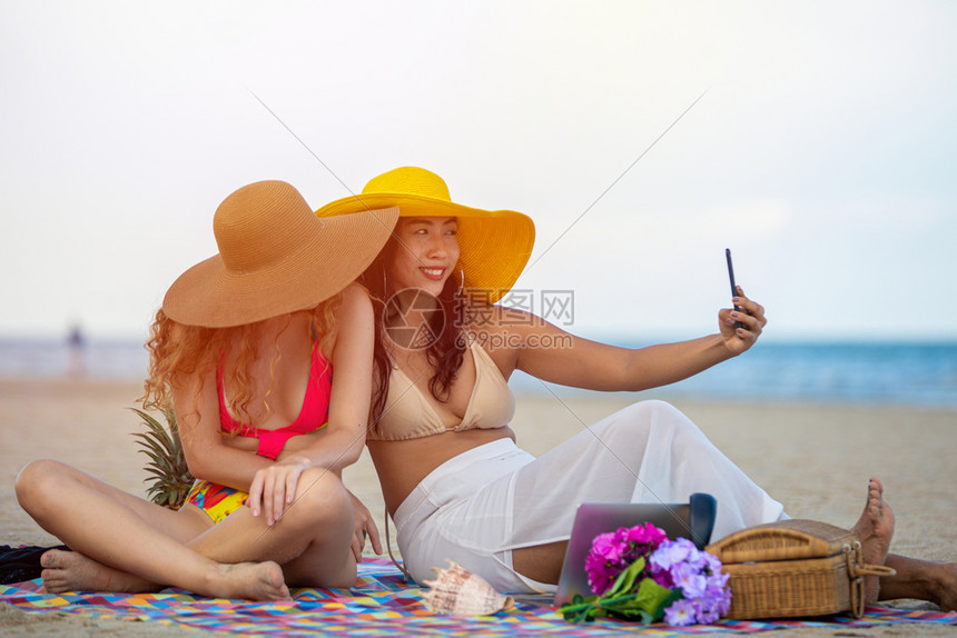 在沙滩上和朋友一起拍照片的女生图片