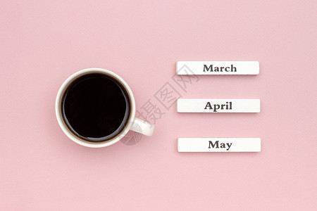 三月你好啊木日历春季月份三四五和一杯黑咖啡指向五月在柔和的粉红色纸背景概念你好五月创意顶视图平躺贺卡木日历春天三月四五和一杯黑咖啡指向五月背景