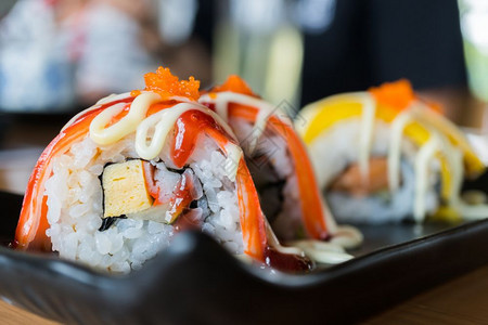 生的螃蟹棒寿司卷和草莓酱黑陶瓷盘上的日本菜风格人饭团图片