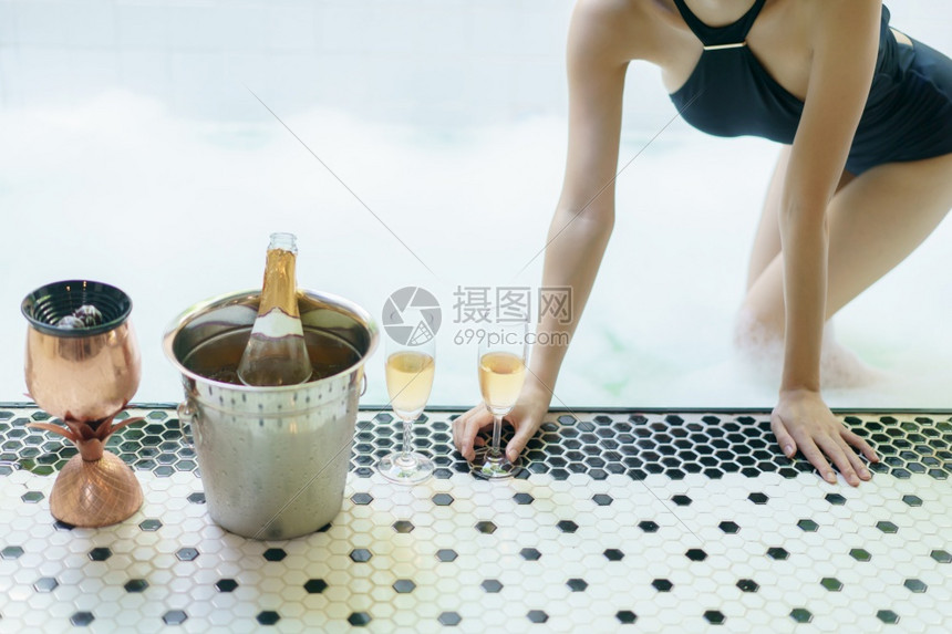 快乐的户外感在泡池中用杯酒与妇女握手图片