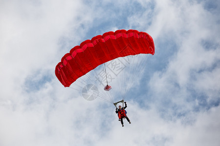 运动降落伞带着红色在蓝天伞带着红色闲暇跳图片