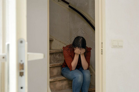 焦虑悲伤的女人独自坐在楼梯上哭泣房子仍然需要翻新建设和的概念特写悲伤的女人独自坐在楼梯上哭泣房子仍然需要翻新建设和的概念坐着装修图片