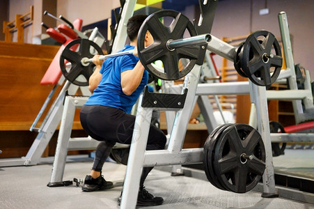 健美运动员杠铃合身适在训练机上做深蹲的人高质量照片适合在训练机上做深蹲的人图片