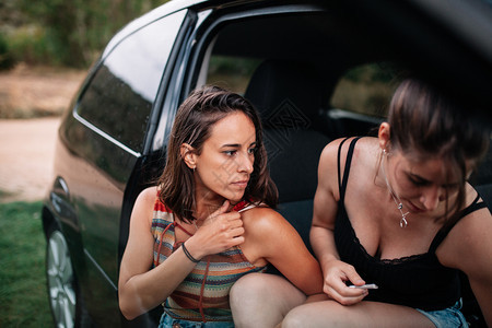 物质两个年轻的女者在车上滚手制香烟吸引人的下雨图片