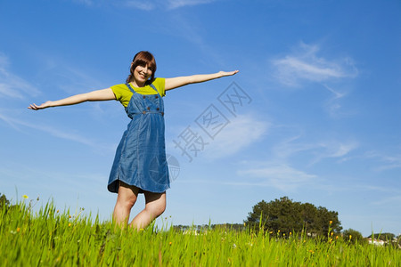 女孩美丽的快乐人在绿草地上张开双臂休息乐趣图片