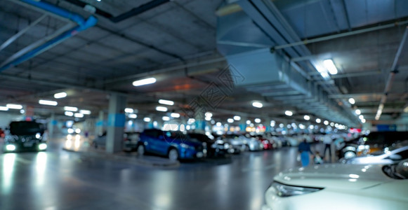 商业里面模糊购物中心的地下停车场开灯模糊汽车驾驶和人们在地下室停车场内行走蓝色的图片