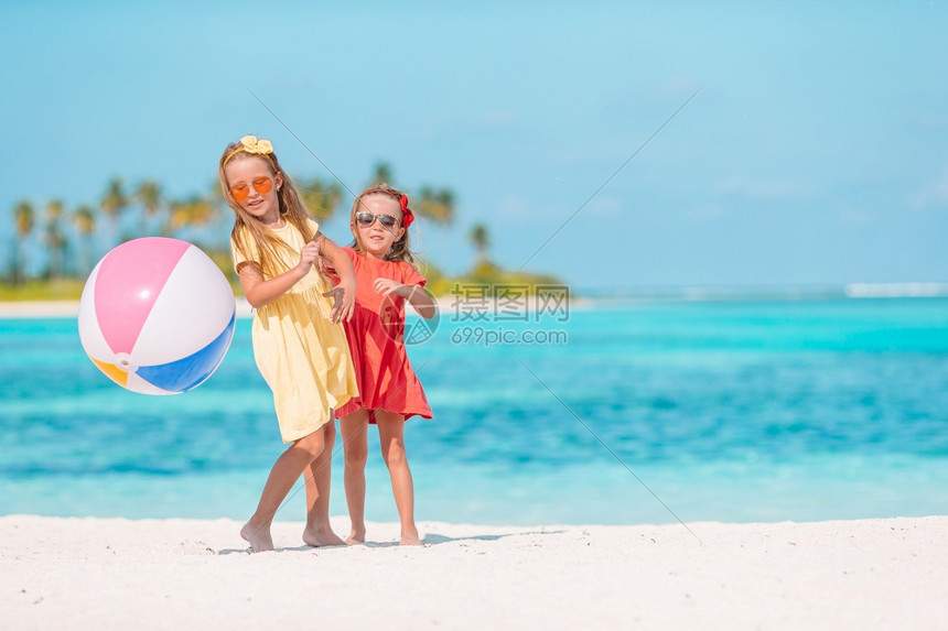 夏天可爱的小女孩在沙滩上玩球小可爱的女孩在沙滩上玩空气球孩子们在海边玩得很开心运动海洋图片