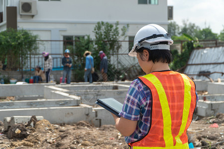 在建筑工地上站着时用平板头戴盔的亚洲女建筑工肖像以背景概念为构筑工程想保持经理人们图片