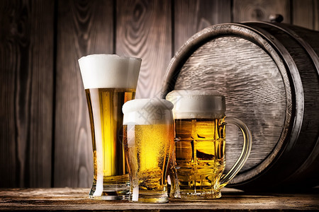 两杯和轻啤酒放在旧木桶背景上两杯和一轻啤酒黑暗的棕色透明图片