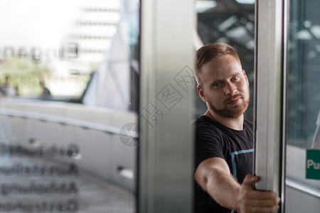 商业建造一种个胡须男子开着玻璃门直看着摄像机图片