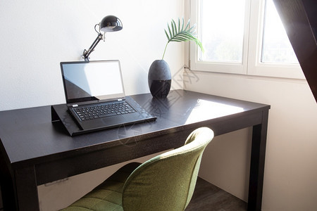 工作场所在靠近窗户的家里桌子上放着笔记本电脑在阳光明媚的日子时尚装饰特写现代室内家庭办公桌咖啡学习灯图片