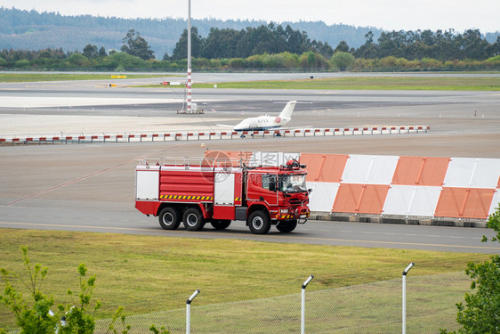 碰撞飞机场在SantiagodeCompostela机场着陆道上乘坐消防车背景为私人喷气飞机的图片