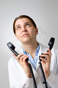 恼火制服女有两台电话接收器的女医生图片
