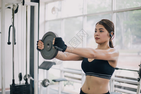 健身房锻炼身体举铁片的年轻女子图片