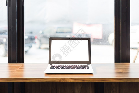 工作区小样在咖啡店的木制桌子上用空白屏幕拍摄笔记本电脑的混装图象键盘图片