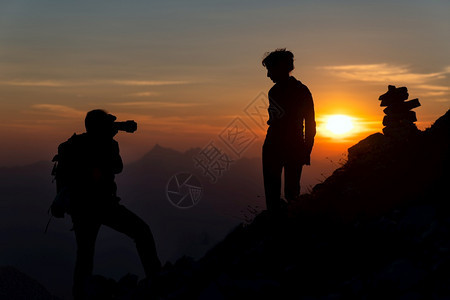 自然天空摄影师在日落时向一个女孩拍摄照片在高山的光影中美丽图片