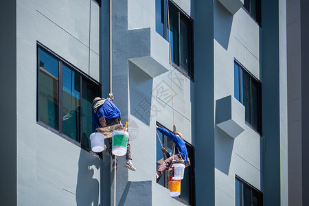 工人业的2名画家挂在绳索上用马带涂漆建筑物的外部危险图片
