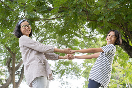 请享用亚洲母亲和女儿站在公园里时手持与笑的侧面观幸福家庭概念尽管孩子图片