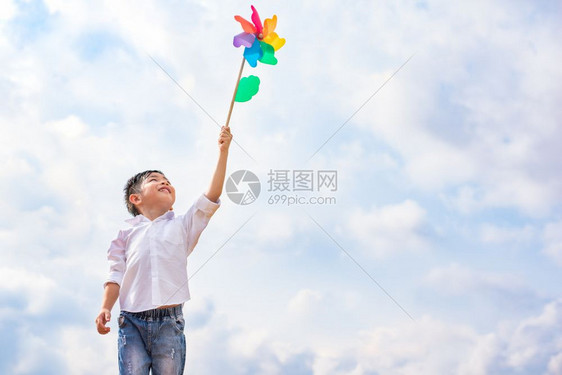 男孩在户外风中抓着多彩的针轮儿童肖像和孩子们玩主题具快乐的人们图片