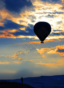 飞明亮的一种在地平线上相爱的一对情侣休眠和早晨天空烈红云背景下的气球充满爱的一对情侣和气球与烈红云在清晨天空上的闪光图片