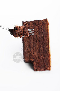 可口叉子上的一块巧克力蛋糕白色背景上的巧克力蛋糕叉子的一块巧克力蛋糕点甜图片