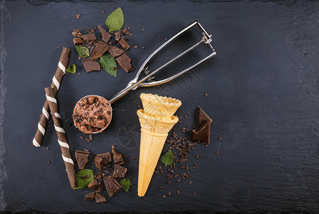 棕色的棍子巧克力冰淇淋加鲜果棒甜圈和巧克力在黑板上专心吃冰淇淋杯子图片