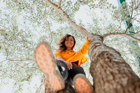 保持分支闲暇妇女享受攀爬树自由概念的妇女图片