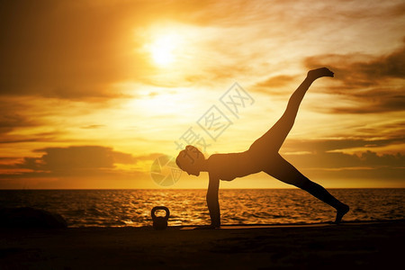 美丽的自然太阳在超现实日落的海边健康概念和锻炼中在超现实日落期间从事瑜伽的妇女图片