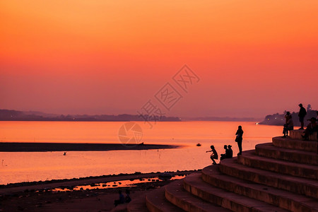 复制经过晚上老挝旅游者和人民放松了湄公河黄昏时的露台观景在湄公河万象老挝西尔维特上飞扬的夕阳天空反射图片