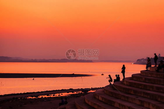 复制经过晚上老挝旅游者和人民放松了湄公河黄昏时的露台观景在湄公河万象老挝西尔维特上飞扬的夕阳天空反射图片