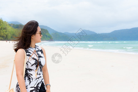 身戴太阳眼镜的美丽女游客微笑地看着泰国海滩上女游客莎吞Tarutao岛公园夏季天空中海滩和的自然景观看着这些海滩和洋的自然景观闲图片