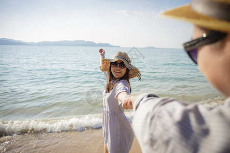 亚洲情侣在海滩上享受度假笑的女友带着她男朋的手走在海滩上相聚一番快乐的男人苏美尔图片