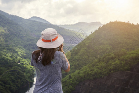 肖像积极的女士快乐旅行者在夏日暑假户外旅行时轻松地用背包和观望令人惊叹的山丘和森林图片