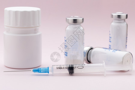 一套注射液和个器套液和个粉红色背景的注射器制药丸目的图片