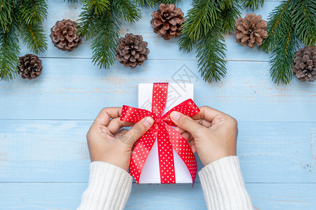 棕色的持有礼品盒圣诞装饰和木背景的松树枝节日概念准备新年快乐和Xmas假日顶端风景等礼物盒的妇女木制板图片
