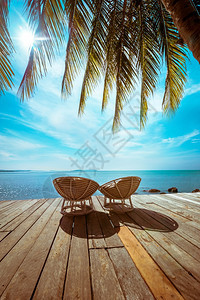 假期具有棕榈树和椅子以放松木梯田的令人惊叹热带海滩景观以及古老风格的旅行背景美丽异国情调图片