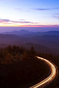 户外森林黎明时的美丽山路天亮时美丽的山路有光向日出月空的卷曲山路背景运动图片